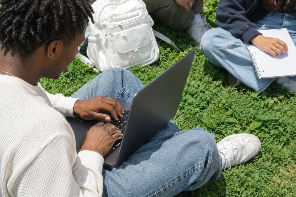 Creator working on a laptop on the grass