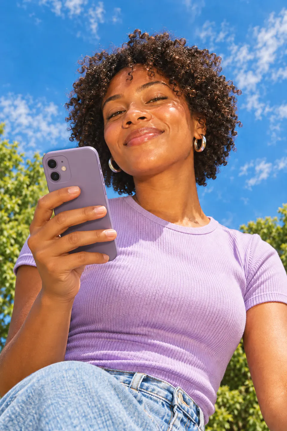 Creator holding her phone under a blue summer sky
